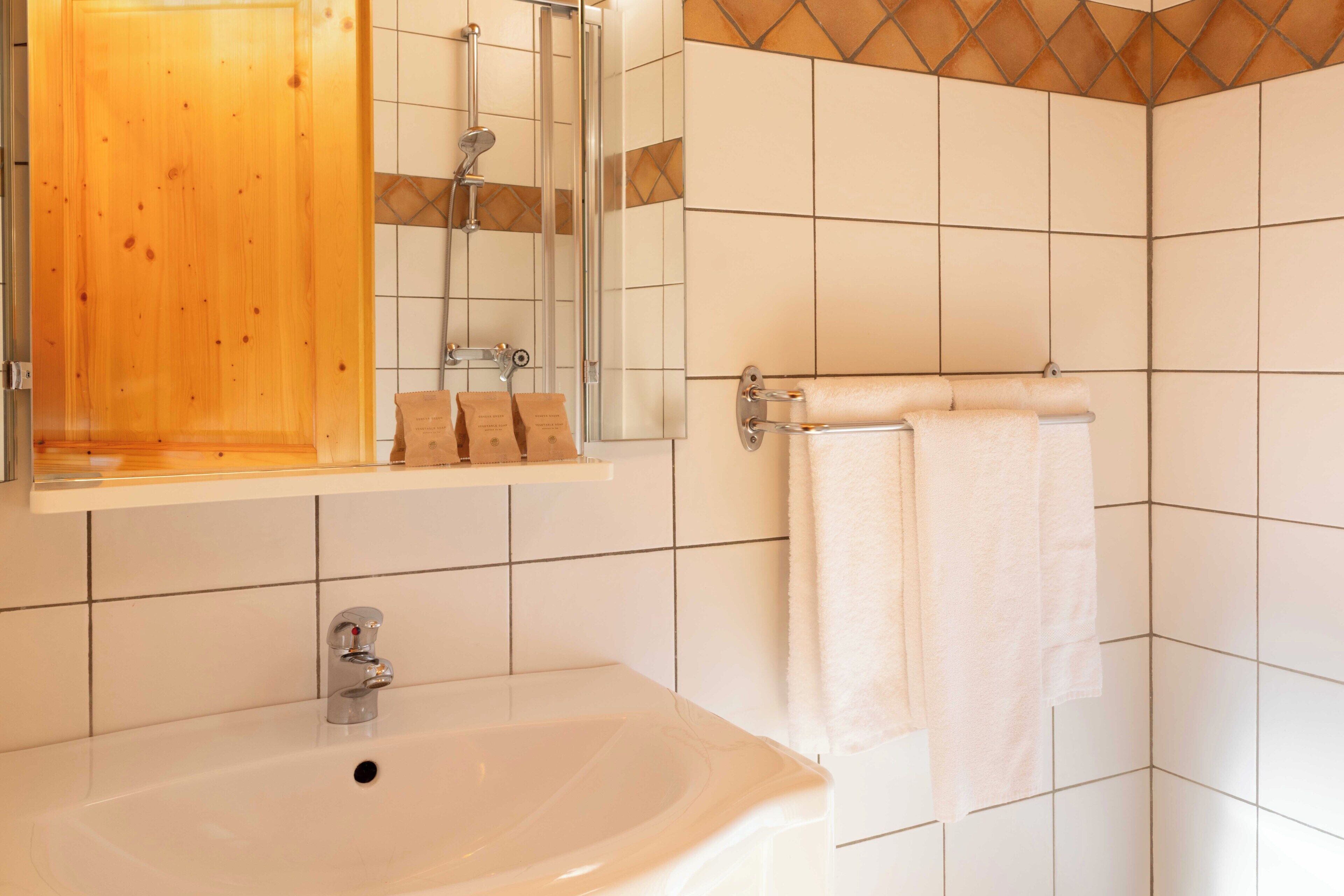 Un baño con puerta de madera, un lavabo, un espejo y un perchero para toallas.