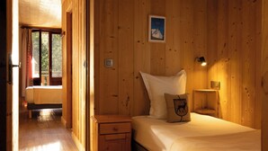 A wooden-paneled room with a bed, bedside table, and a framed picture on the wall. - L’Arveyron Open House (Chamonix-Mont-Blanc)