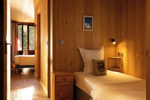 A wooden-paneled room with a bed, bedside table, and a framed picture on the wall.