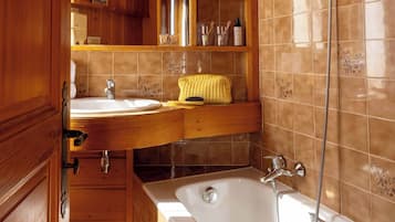 Un baño de cabaña de madera con bañera, lavabo y ducha.