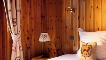 A wooden-paneled room with a bed, a nightstand, a lamp, and a decorative pillow.