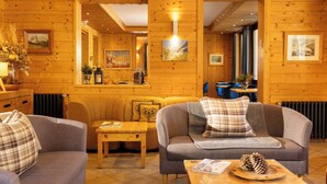 A cozy log cabin interior with a sofa, a coffee table, and a dining area. - L’Arveyron Open House (Chamonix-Mont-Blanc)