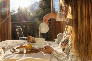 A person pouring a beverage into a cup on a table with a tray of food and a glass of juice. - L’Arveyron Open House (Chamonix-Mont-Blanc)