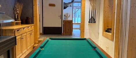A pool table in a room with wooden cabinets and a door leading to a balcony.