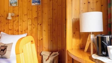 Una habitación de madera con una cama, una lámpara, un hervidor y una maleta.