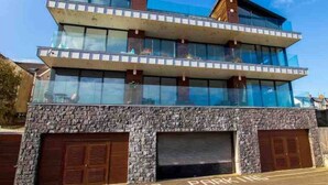 A modern building with a glass facade, two levels, and a stone base. - No2 Sandy Bay , Luxury Beachfront Apartment (Portrush)