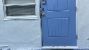 A blue door with a letter 'B' on it, a small window with a shutter, and a decorative metal piece at the base.