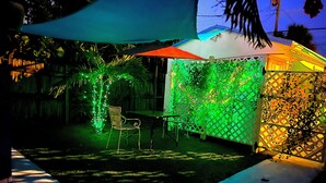A patio area with a table and chairs, a covered seating area, and a decorative fence.