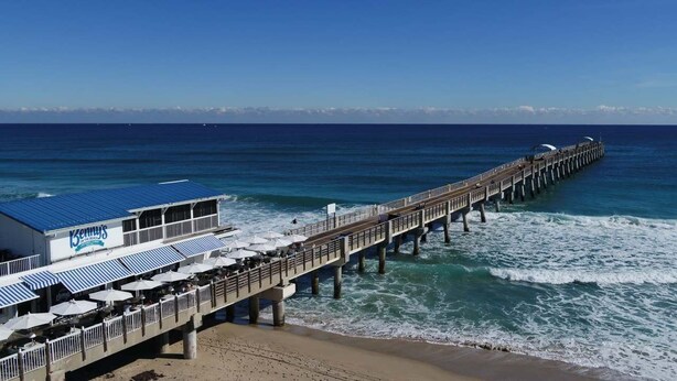 A pier extending into the ocean with a restaurant named "Kenny's" on the left side.