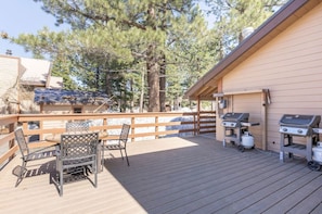 Enjoy al fresco dining on the deck, which features a table and chairs, barbecue grills, and a railing.