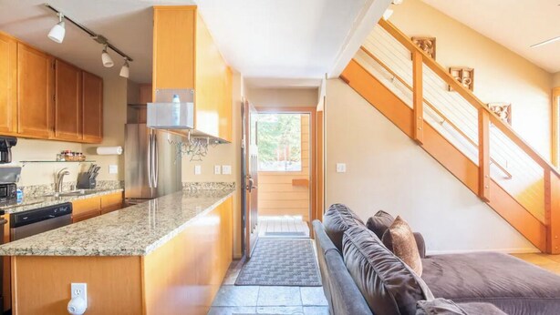 Une cuisine moderne dotée de plans de travail en granit, d’armoires en bois et d’appareils électroménagers en acier inoxydable.