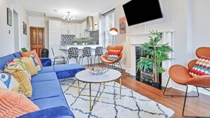 A modern living room with a blue sofa, a coffee table, and a fireplace. - Central Lanes Pad | By My Getaways | Free parking for one car (Brighton)