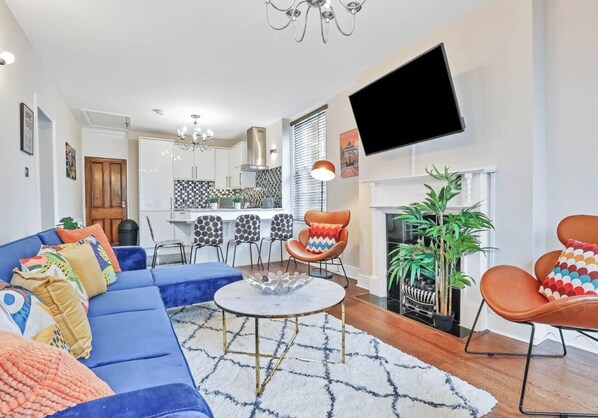 A modern living room with a blue sofa, a coffee table, and a fireplace.