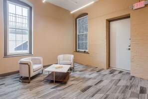 A room with two white armchairs, a wooden coffee table, a large window, and an exit sign.