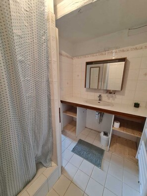 Bathroom features a sink, mirror, and shower curtain.