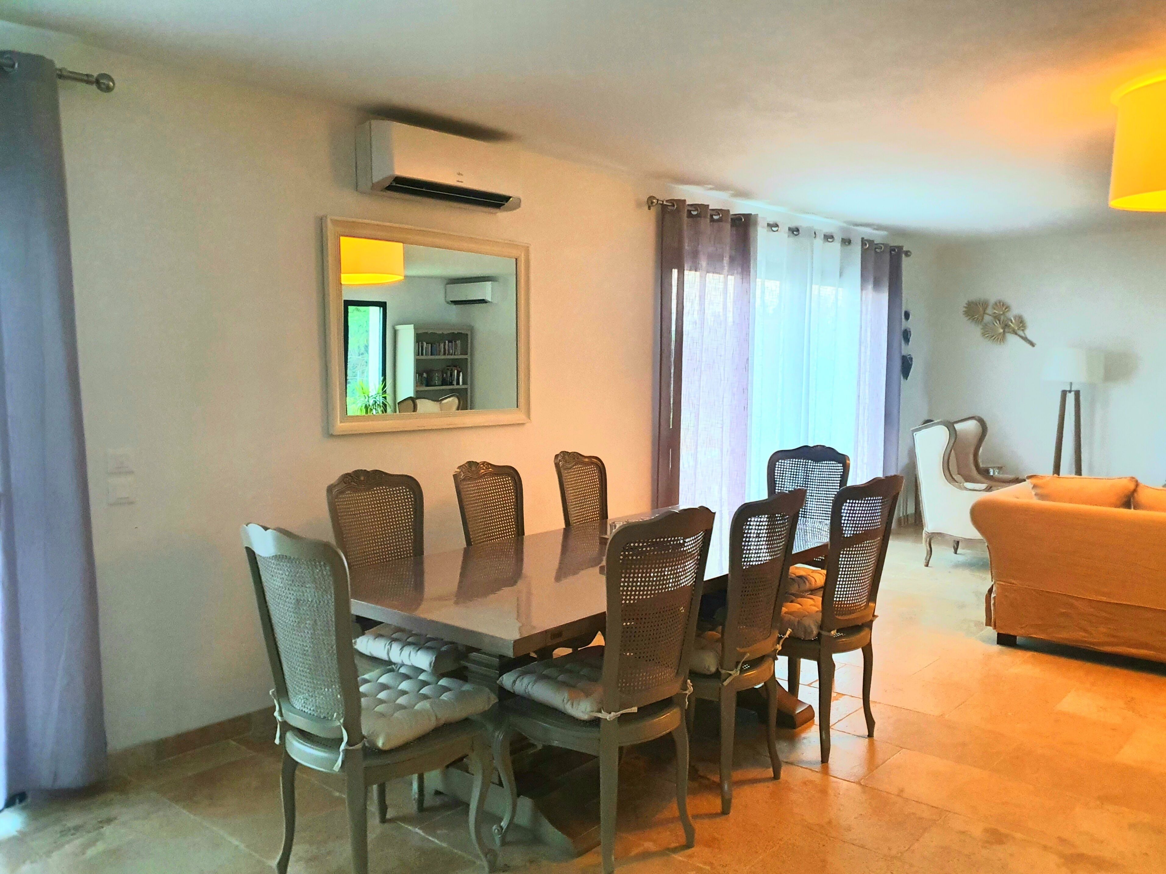 Ein Essbereich mit Tisch und Stühlen, ein Spiegel und ein Wohnzimmer mit Sofa und Lampe.