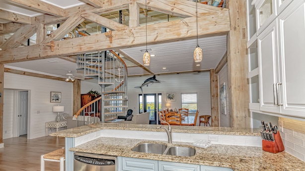A spacious kitchen with granite countertops, a stainless steel dishwasher, and a built-in knife block.