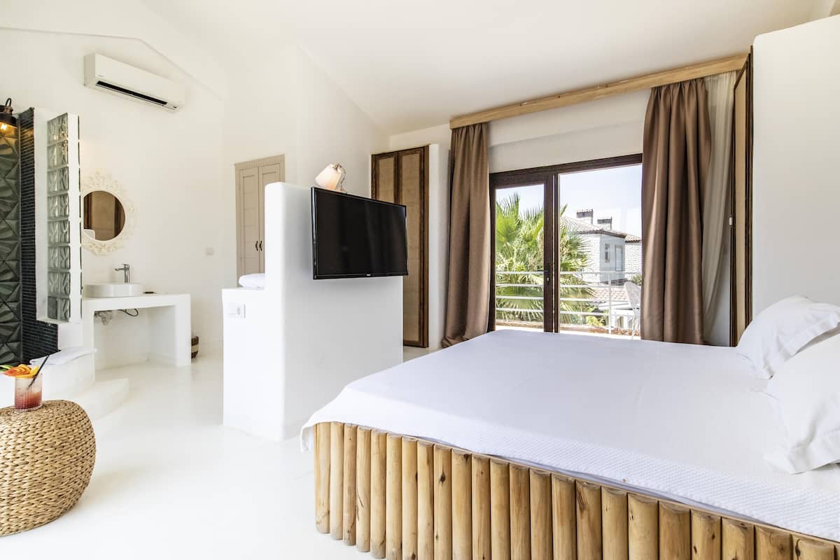 Un dormitorio moderno con una cama grande, televisor, baño y vistas al exterior.