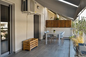 A patio with a table and chairs, a wooden crate, and a potted plant. - Discover Athens from an Upscale flat in Koukaki! (Αθήνα)