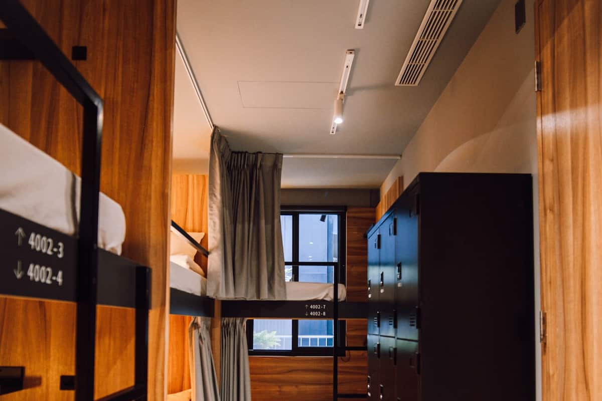 Una habitación de hotel con literas, un armario y una ventana con cortinas.