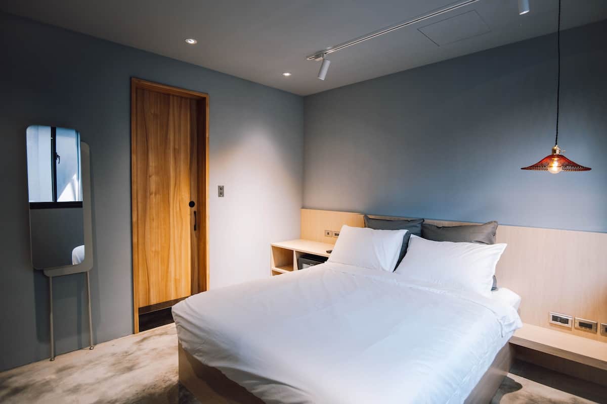 Un dormitorio moderno con una cama grande, puerta de madera y un escritorio con silla.