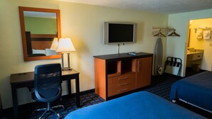 Habitación de hotel con escritorio, silla, televisor, armario y dos camas.