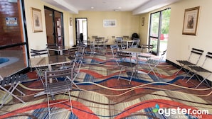 Una habitación de hotel con un ventanal grande, alfombra estampada y varias sillas plegables.