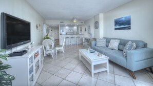 A modern living room with a flat-screen TV, white furniture, and a grey sofa. - Bluewater Resort 902 - Beautiful 2 Bedroom/2 Bath Condo, Ocean Front View, Indoor/Outdoor pool, Hot Tub (Myrtle Beach)