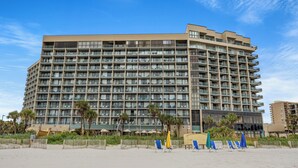 A multi-story hotel with a uniform facade, balconies, and a beachside location.