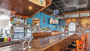 Zona de bar con mostrador de madera, taburetes y una pantalla de televisión.