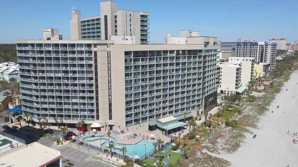 A large hotel with multiple floors, a swimming pool, and a beachside location. - SAND DUNES SOUTH TOWER 1150 AND 1149 (Myrtle Beach)