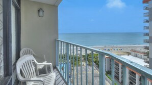 A balcony with white plastic chairs, a view of the beach, and a clear sky. - SAND DUNES SOUTH TOWER 1150 AND 1149 (Myrtle Beach)