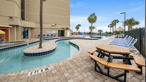 A swimming pool area with lounge chairs and a picnic table, surrounded by palm trees and a building. - SAND DUNES SOUTH TOWER 1150 AND 1149 (Myrtle Beach)