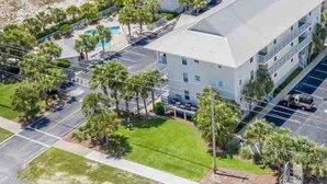 Un hôtel à plusieurs étages doté d’une piscine, entouré de palmiers et comprenant un parking.