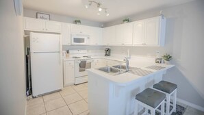 Une cuisine moderne avec des meubles blancs, un four à micro-ondes encastré, une cuisinière et un évier.