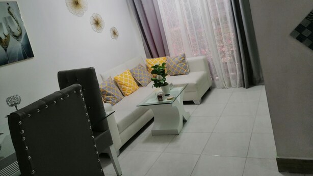 A modern living room with a white sofa, a glass coffee table, and a black armchair.