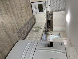 Enjoy cooking in this well-equipped kitchen with a stainless steel refrigerator, ample cabinetry, and a granite countertop.