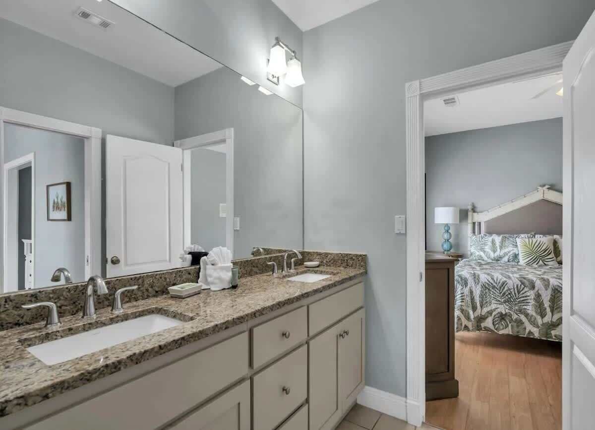A bathroom with a double sink, a large mirror, and a light fixture above the mirror.