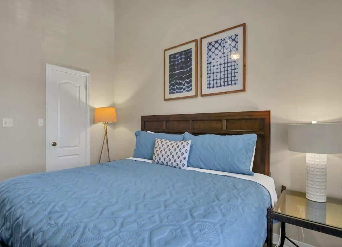 Une chambre à coucher comprenant un lit, deux lampes fixées au mur et deux œuvres d’art encadrées.