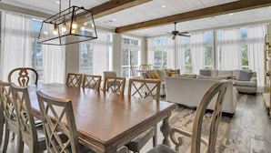 Un'ampia sala da pranzo con tavolo e sedie in legno, una moderna lampada a sospensione e ampie finestre che offrono vista sull'esterno.