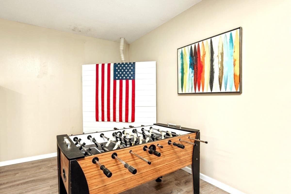 Ein Fußballtisch in einem Raum mit einer großen amerikanischen Flagge und einem farbenfrohen, abstrakten Gemälde an der Wand.