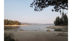 Luonnonkaunis maisema, jossa on järvi, hiekkaranta ja tiheä metsä.