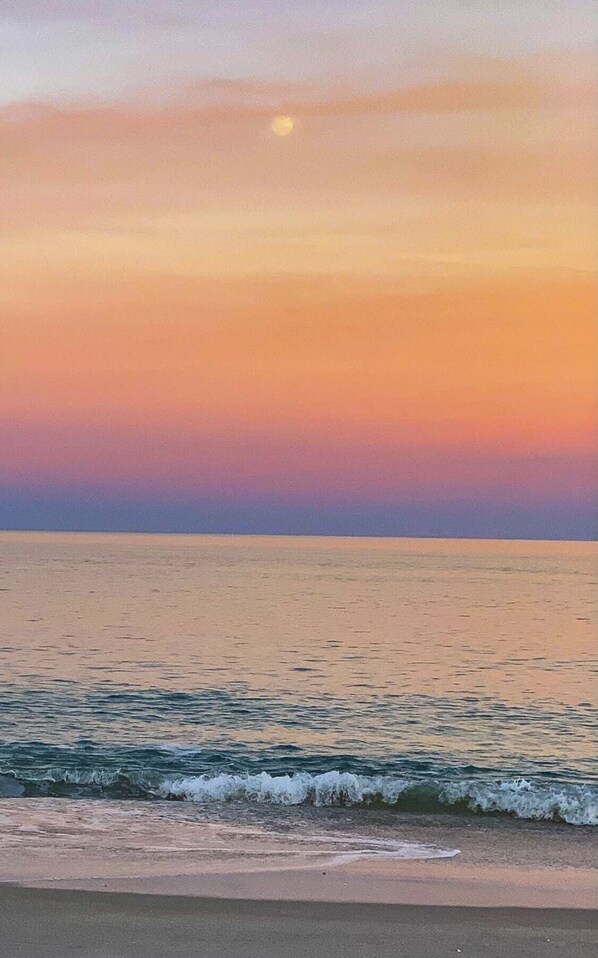 Eine Strandansicht mit ruhiger See und Sonnenuntergang.