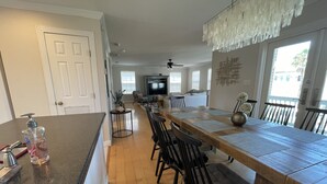 A spacious kitchen with a long wooden dining table, black chairs, and a central island with a sink and soap dispenser. - Amazing 5BR  Entire house, private heated pool & Hot Tub 3 min walk to beach. (South Padre Island)