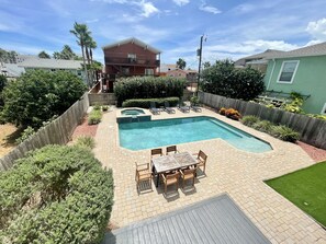 A backyard with a swimming pool, a wooden deck, and a table with chairs.
