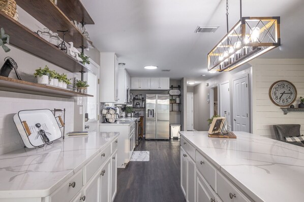 A modern kitchen with white cabinetry, a central island, and a hanging light fixture.