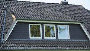 A house with a dark grey tiled roof, a dormer window, and a brick facade. - Lüneburg 0 meters? Welcome! Beautiful 95 sqm, 3 rooms, 1-6 pers., large bathroom, garden (Reppenstedt)