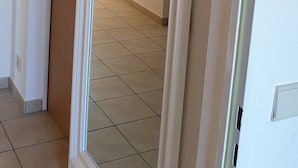 A hallway with a door leading to a room with a tiled floor and a painting on the wall. - Lüneburg 0 meters? Welcome! Beautiful 95 sqm, 3 rooms, 1-6 pers., large bathroom, garden (Reppenstedt)