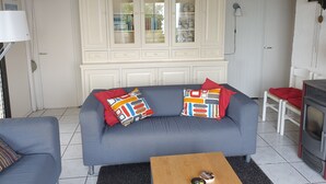 A living room with a grey sofa, a wooden coffee table, a white cabinet with glass doors, and a red chair. - Tignale / Hasewinkel (Tignale BS)