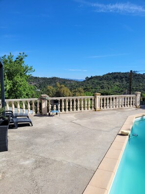 A pool area with a stone balustrade, lounge chairs, and a view of a forested hillside. - Villa with breathtaking view of the Massif des Maures (Vidauban)
